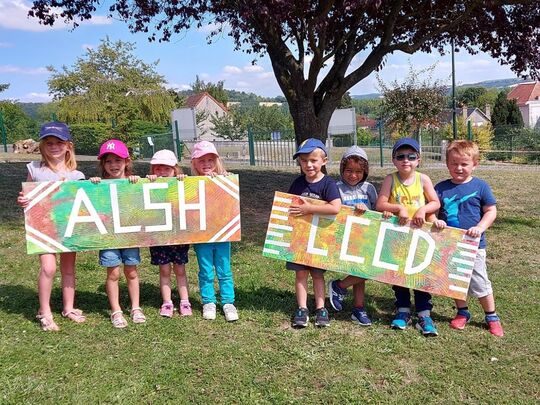 Un groupe d'enfants de l'accueil de loisirs a réalisé des pancartes " ALSH CCCD ", ils sont heureux de poser avec.